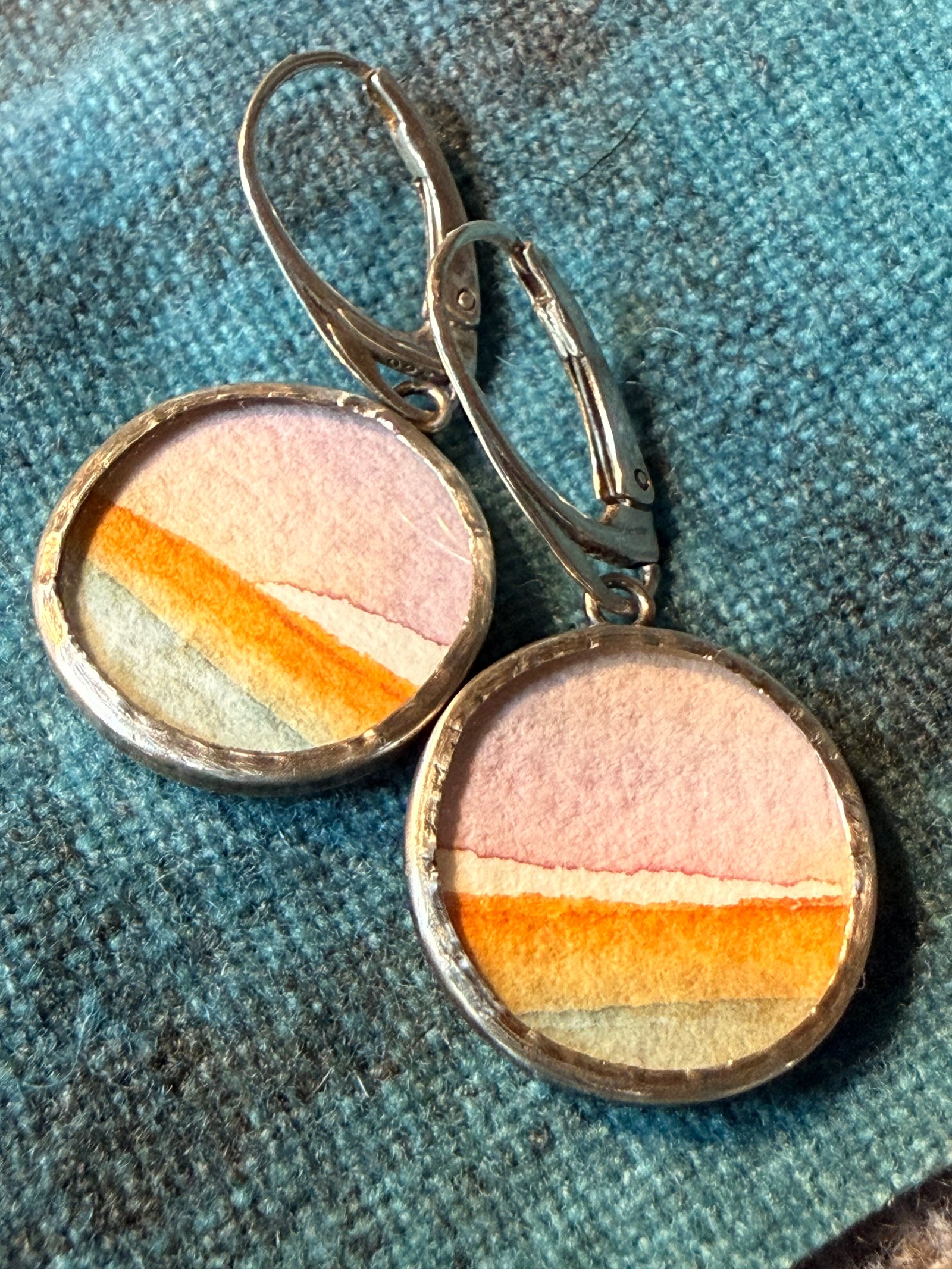 Round lever-back earrings featuring pink, orange, and sage watercolor stripes in metal bezels